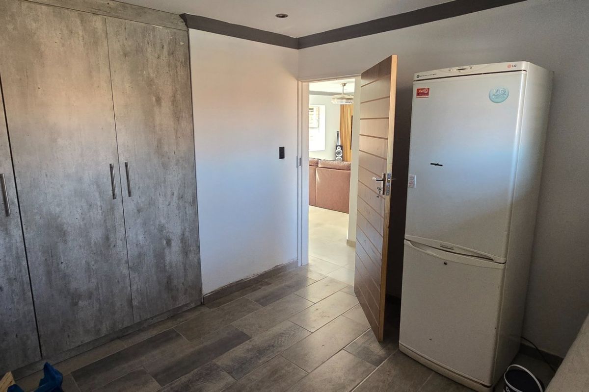 Bedroom featuring built-in cupboards, tiled flooring, and recessed lighting, with an open doorway leading to the adjacent living area.