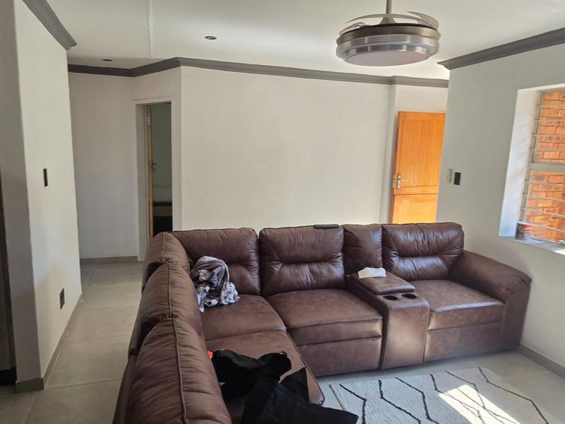 A living room featuring tiled flooring, recessed lighting, a ceiling fan, and built-in storage cupboards.