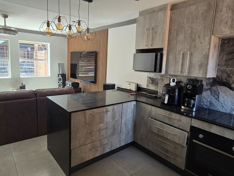 Modern open-plan living area featuring a contemporary kitchen with stone countertops, built-in oven, and a stylish slatted wood feature wall in the lounge.