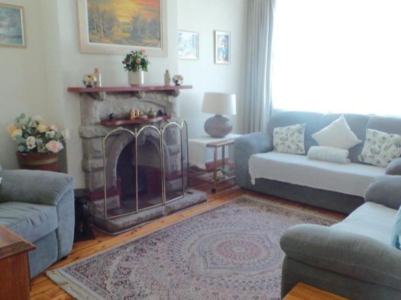 A cozy living room featuring a traditional stone fireplace and warm timber flooring, offering a comfortable and inviting atmosphere.