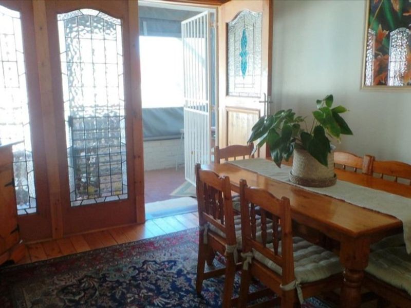 Dining area featuring traditional timber flooring and decorative leaded glass doors leading to an outdoor patio space.