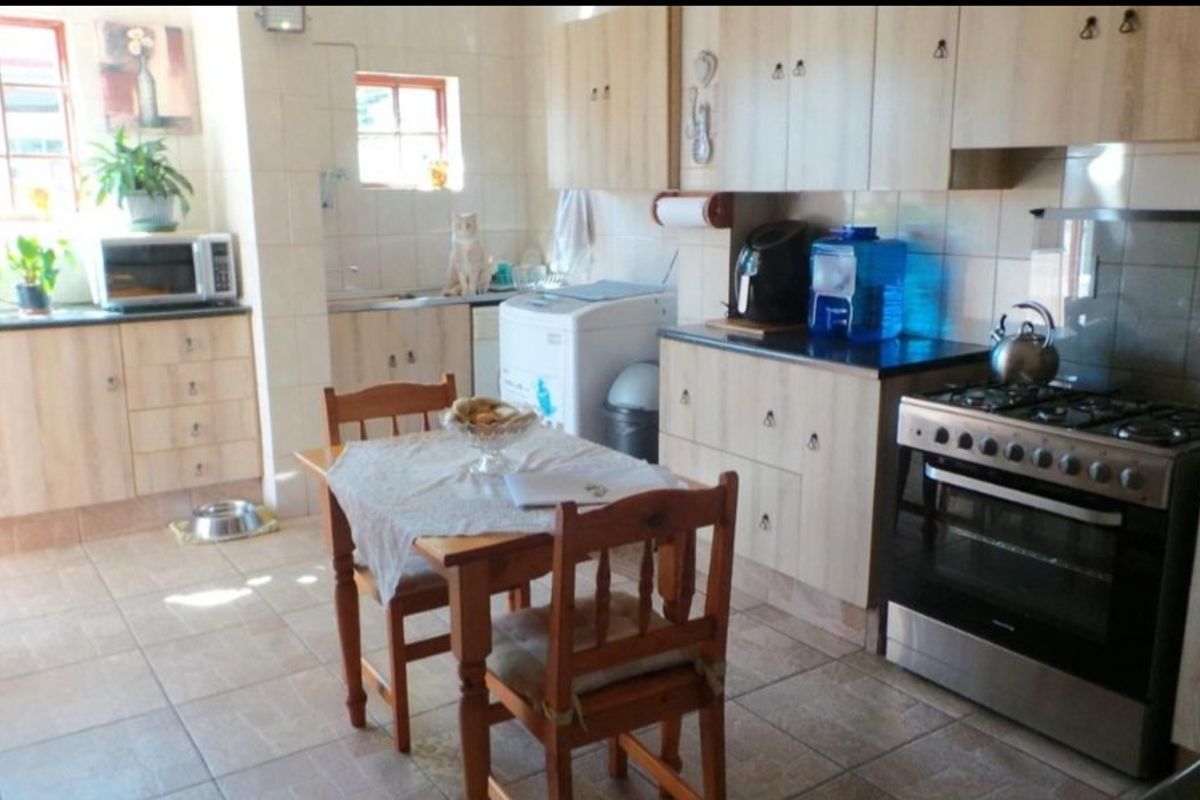 A functional kitchen featuring light wood-finish cabinetry, tiled flooring, a gas stove with oven, and a tiled backsplash.