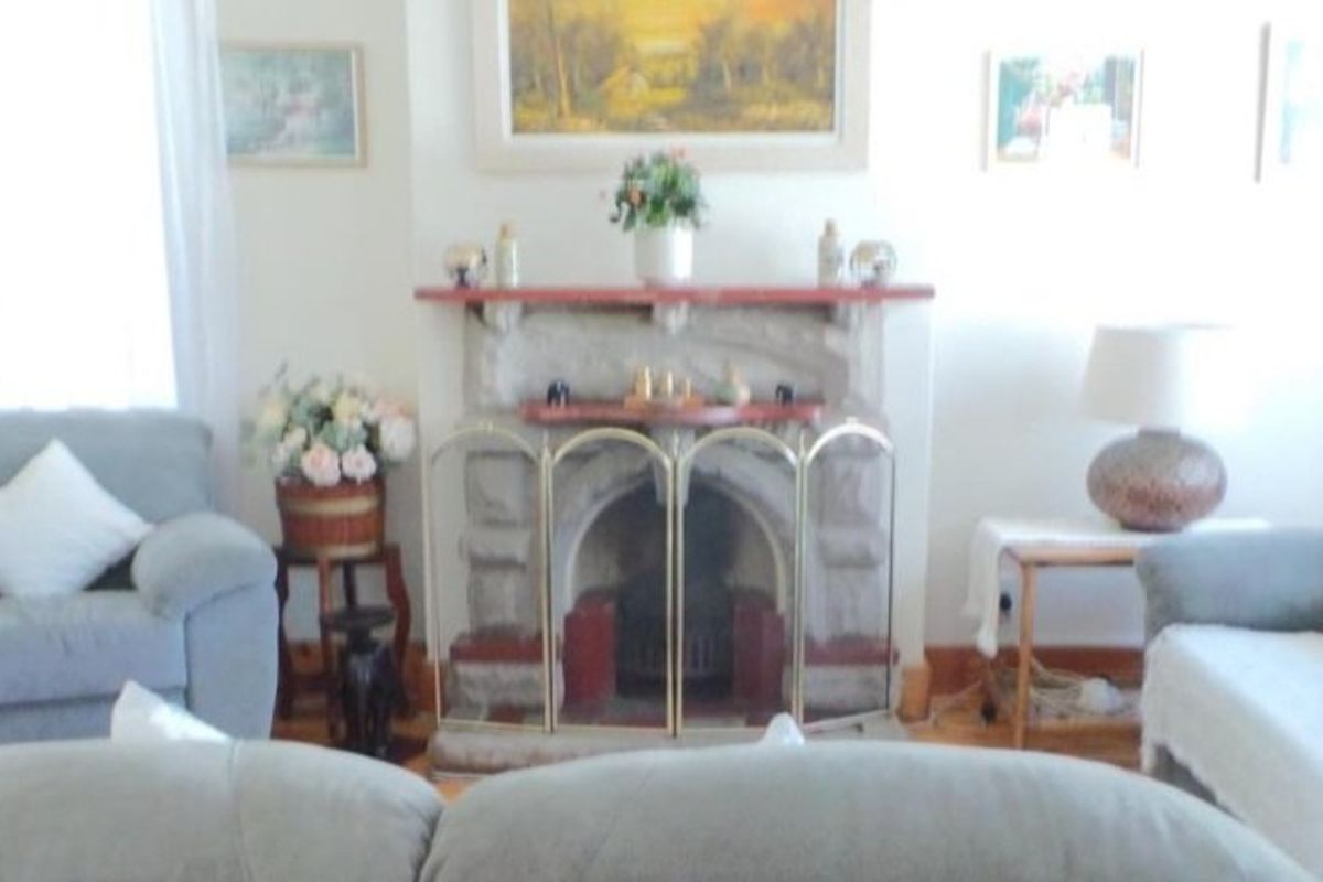 A cozy living room featuring a traditional stone fireplace and timber flooring, providing a warm and inviting atmosphere.