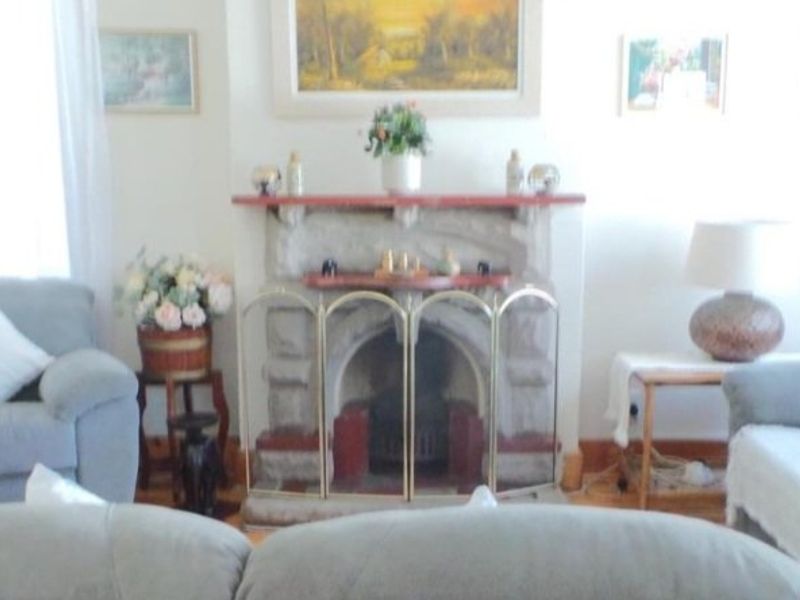 A cozy living room featuring a traditional stone fireplace and timber flooring, providing a warm and inviting atmosphere.