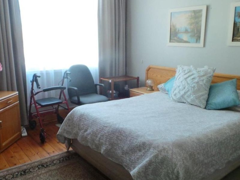 A comfortable bedroom featuring warm timber flooring and a large window that allows for natural light.
