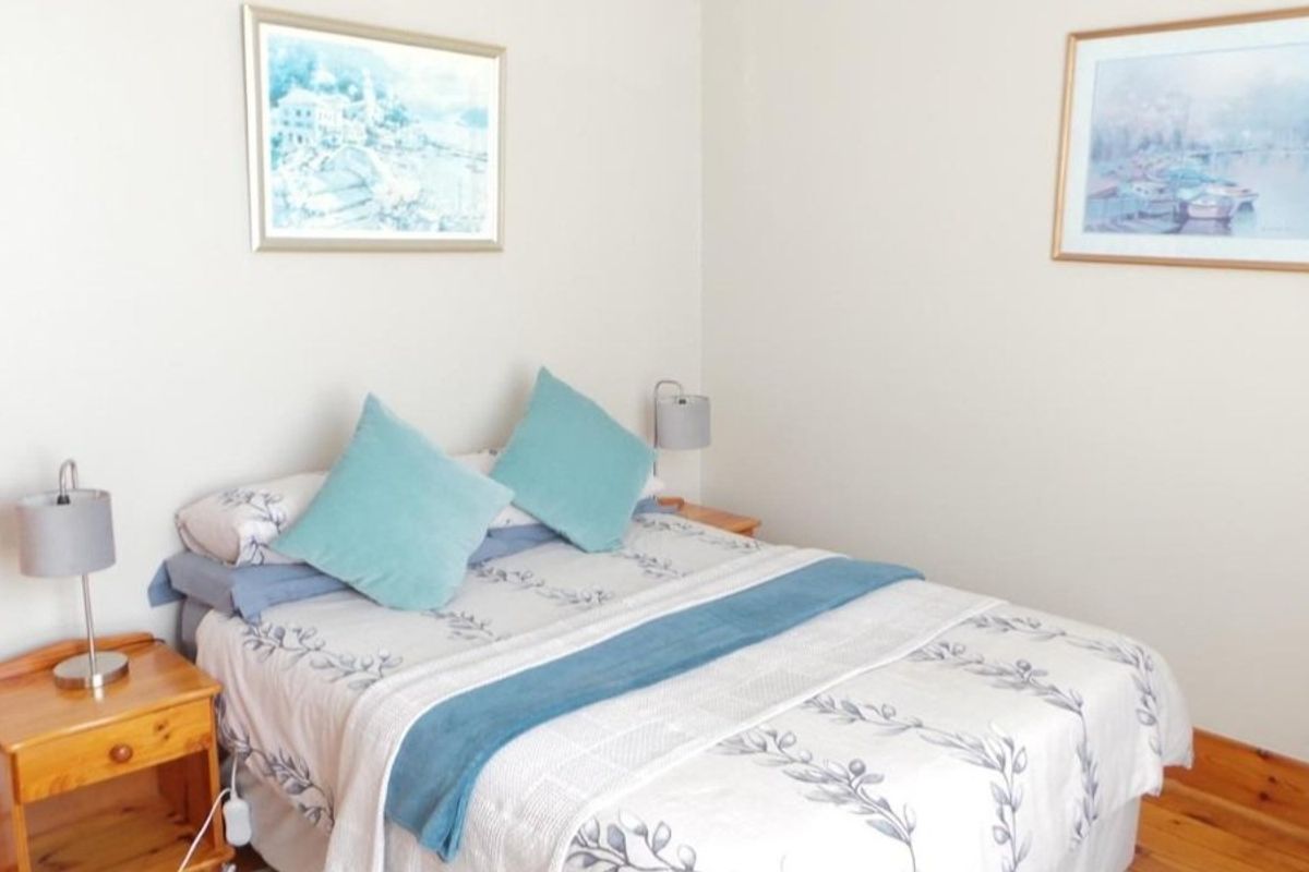 A cozy bedroom featuring warm timber flooring and wall-mounted lighting, providing a comfortable and inviting sleeping space.