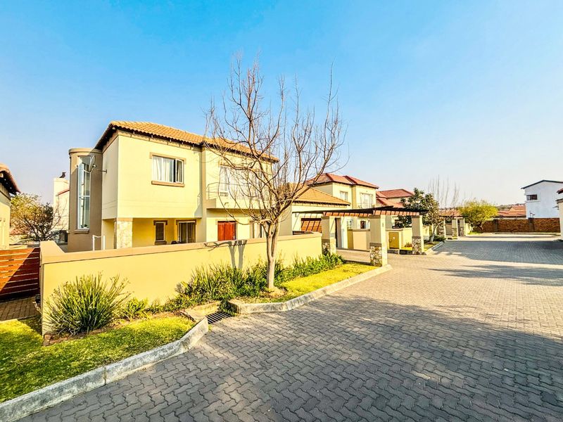 A view of the residential street showing the exterior facades of the houses, paved driveways, and established boundary walls.