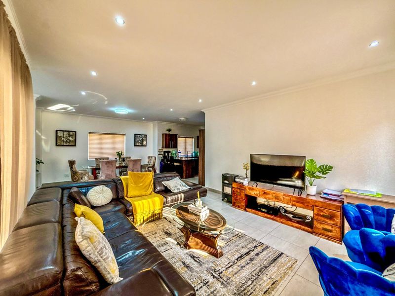 Spacious open-plan living and dining area featuring tiled flooring, recessed downlighting, and neutral wall finishes, creating a bright and functional family space.