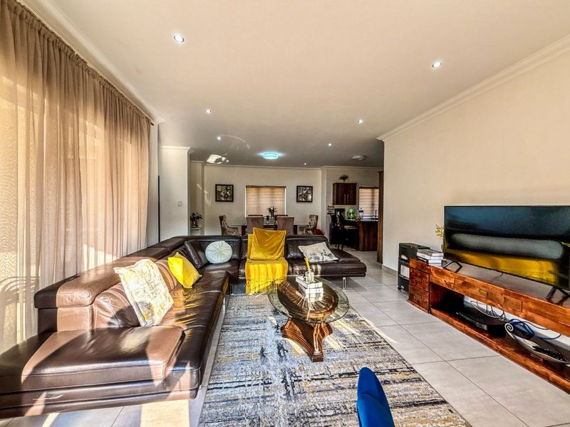 Spacious open-plan living and dining area featuring neutral tiled flooring, recessed downlighting, and a seamless flow into the adjacent kitchen space.