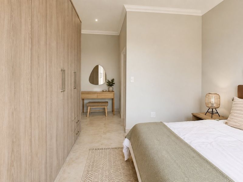 A well-maintained bedroom featuring neutral tiled flooring, extensive built-in wooden cupboards, and recessed ceiling lighting.