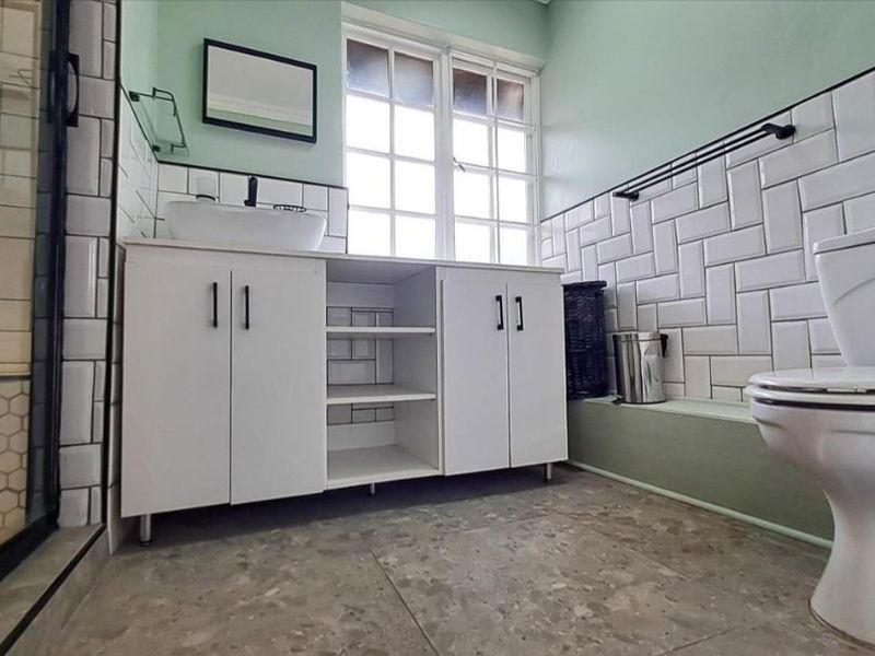 Modern bathroom featuring a white vanity with vessel sink, subway tile backsplash, glass shower enclosure, and a toilet.