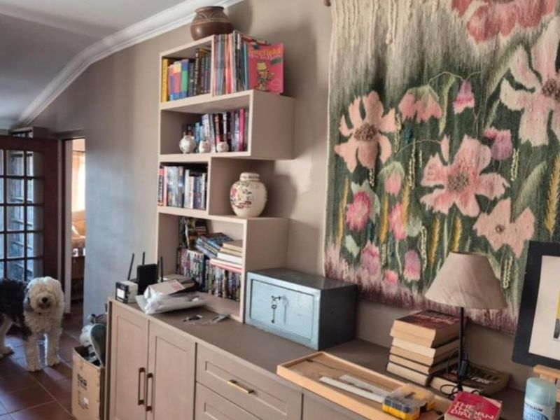 A living area featuring built-in cabinetry with integrated shelving, crown molding, and tiled flooring.