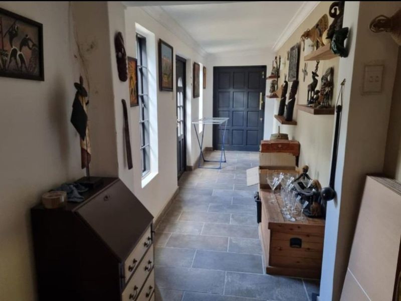 A functional hallway featuring tiled flooring, coving, and a panelled front door, providing a clear transition space within the home.