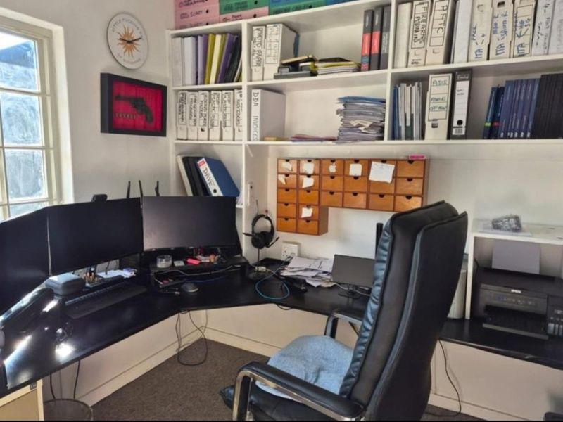 A functional home office featuring extensive built-in shelving and a wrap-around desk configuration, providing ample workspace and storage.