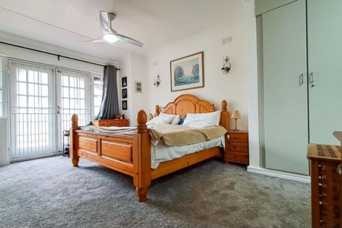 Spacious bedroom featuring a ceiling fan, built-in wardrobe, and glass sliding doors providing access to the exterior.