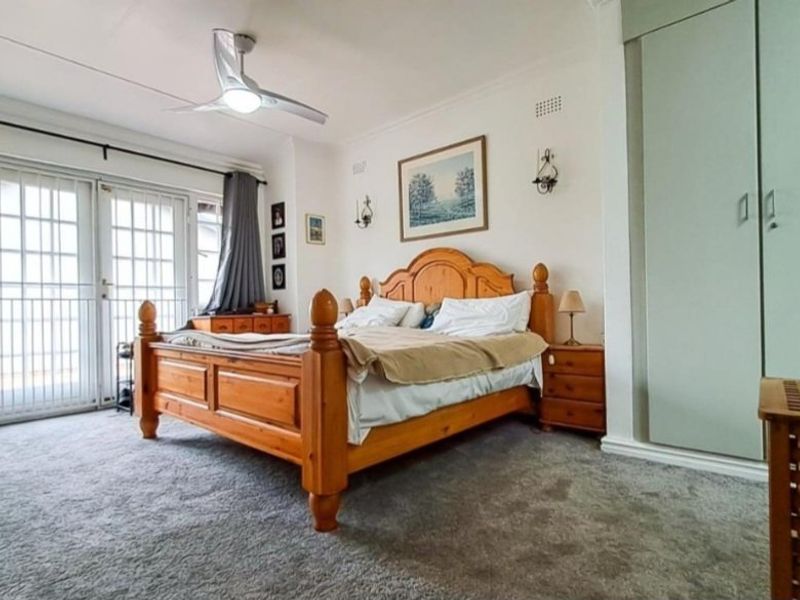 Spacious bedroom featuring a ceiling fan, built-in wardrobe, and glass sliding doors providing access to the exterior.