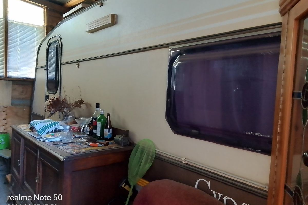 An indoor space featuring a parked caravan or trailer unit used as a storage or living area.