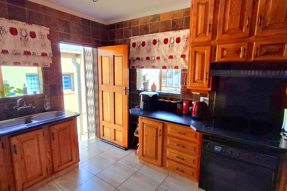 A functional kitchen featuring wooden cabinetry, black granite countertops, a double sink, and built-in appliances with direct access to the exterior.