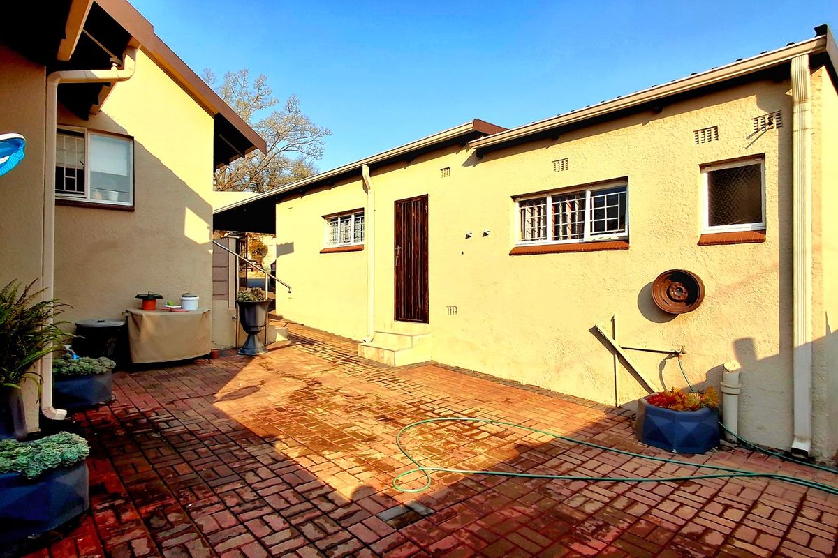 A rear courtyard area featuring brick paving, security-fitted windows, and a secure entrance door, providing a functional outdoor space.