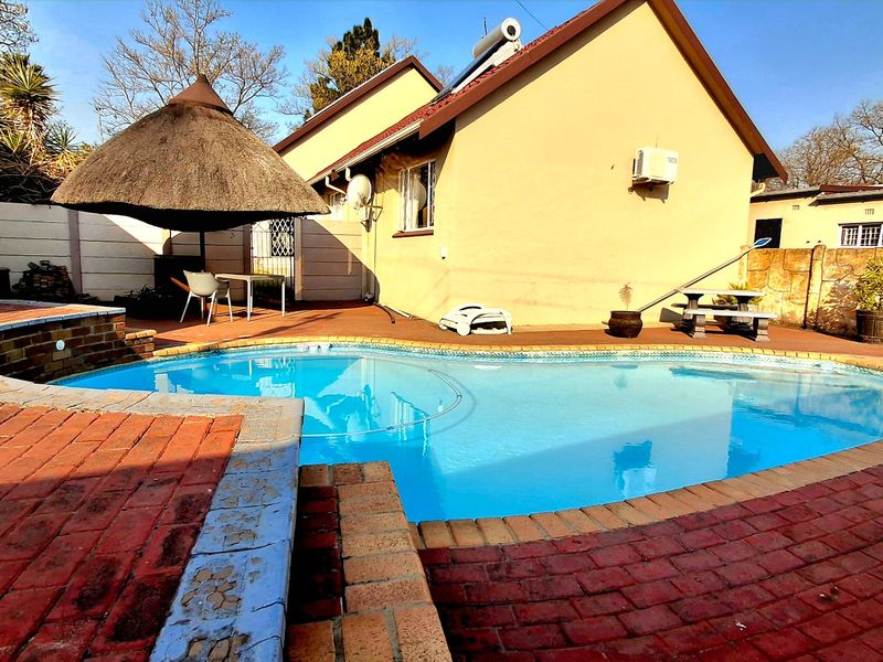 Outdoor pool area featuring a swimming pool with brick paving surround, boundary walls, and a solar geyser installed on the roof.