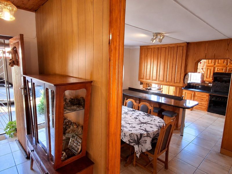 Open plan kitchen and dining area featuring wood paneling, tiled floors, and a breakfast bar, offering a functional layout with potential for modernization.