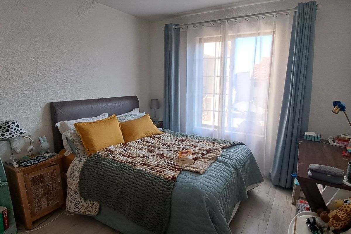A cozy bedroom featuring laminate flooring and a large window that allows for natural light.