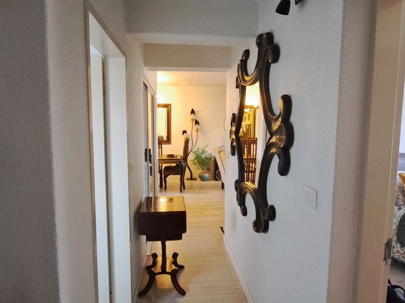 A bright hallway connecting the living area and bedroom, featuring tiled flooring and built-in shelving units.
