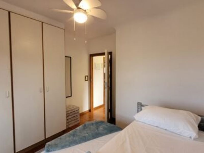 A functional bedroom featuring built-in cupboards, a ceiling fan, and direct access to the hallway.