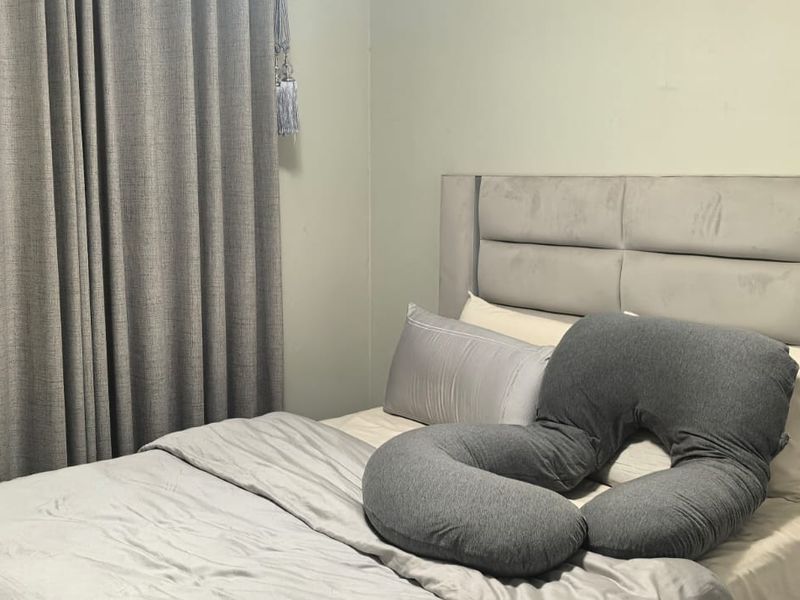 A bedroom featuring neutral wall tones and full-length curtains, providing a simple and functional sleeping space.