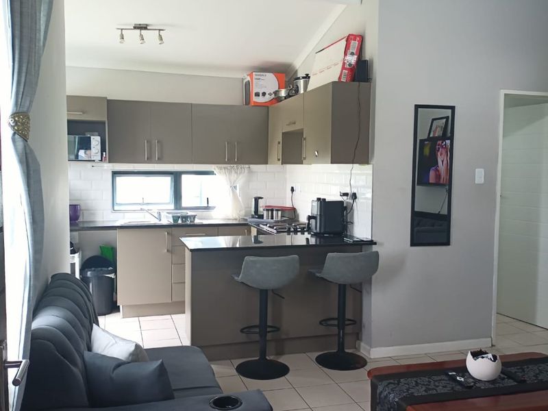 Open plan living area featuring a modern kitchen with built-in cabinetry, granite countertops, gas hob, and tiled flooring throughout.