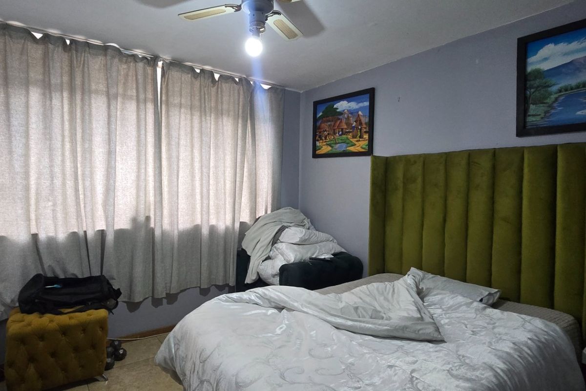 A bedroom featuring tiled flooring and a ceiling fan, providing a functional space for rest.