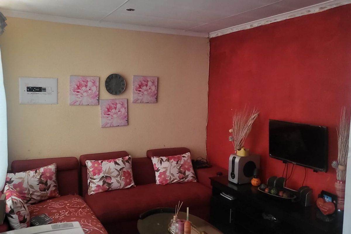 A living room featuring a bold red accent wall, recessed ceiling lighting, and an integrated electrical distribution board.