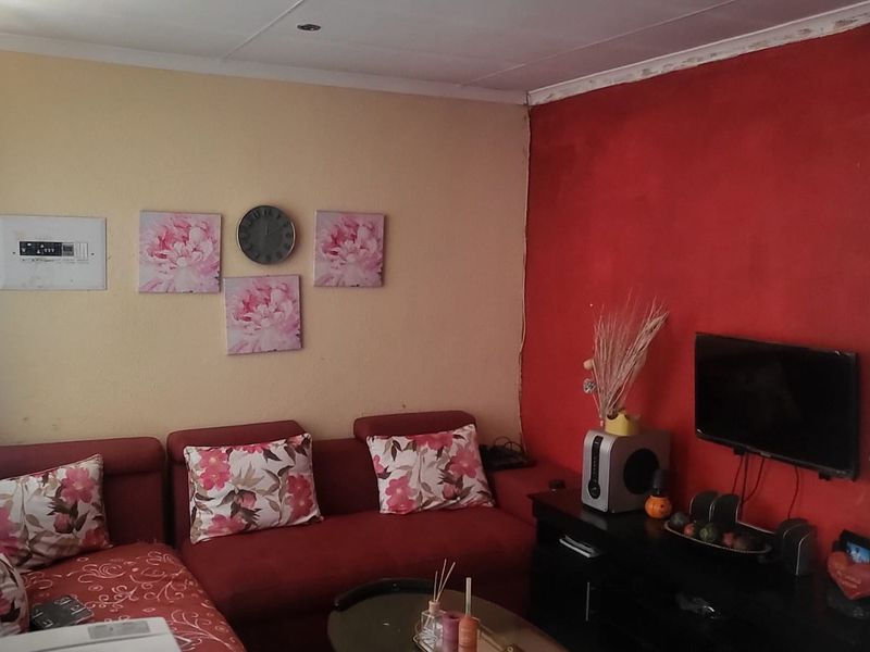 A living room featuring a bold red accent wall, recessed ceiling lighting, and an integrated electrical distribution board.