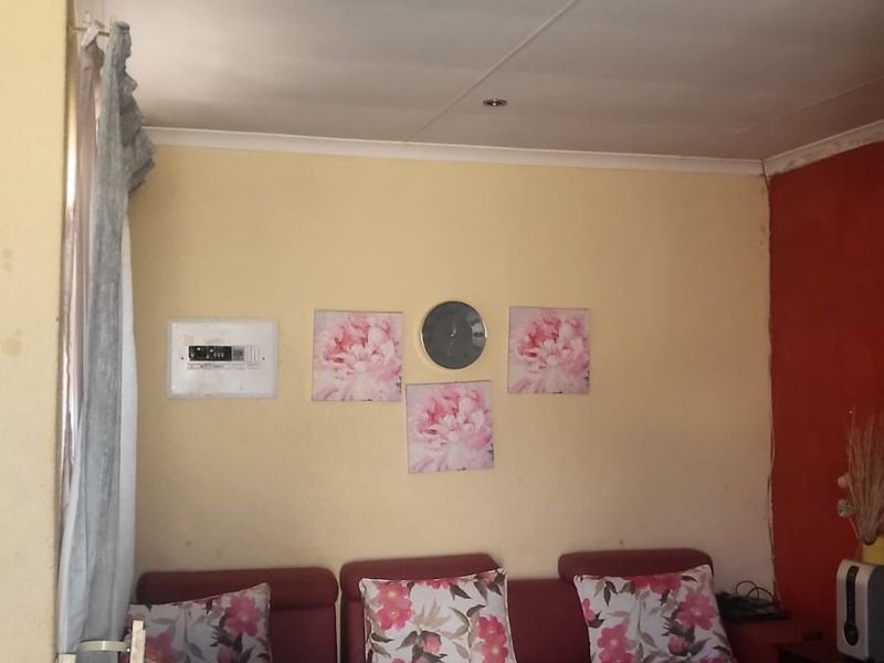 A living room area featuring tiled flooring, recessed ceiling lighting, and a wall-mounted electrical distribution board.