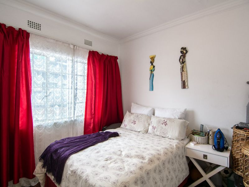 A functional bedroom featuring a window with integrated ventilation grilles and decorative cornice detailing.