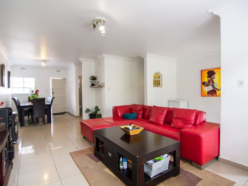 Spacious open-plan living and dining area featuring neutral tiled flooring, decorative ceiling cornices, and a recessed wall niche, offering a versatile layout.