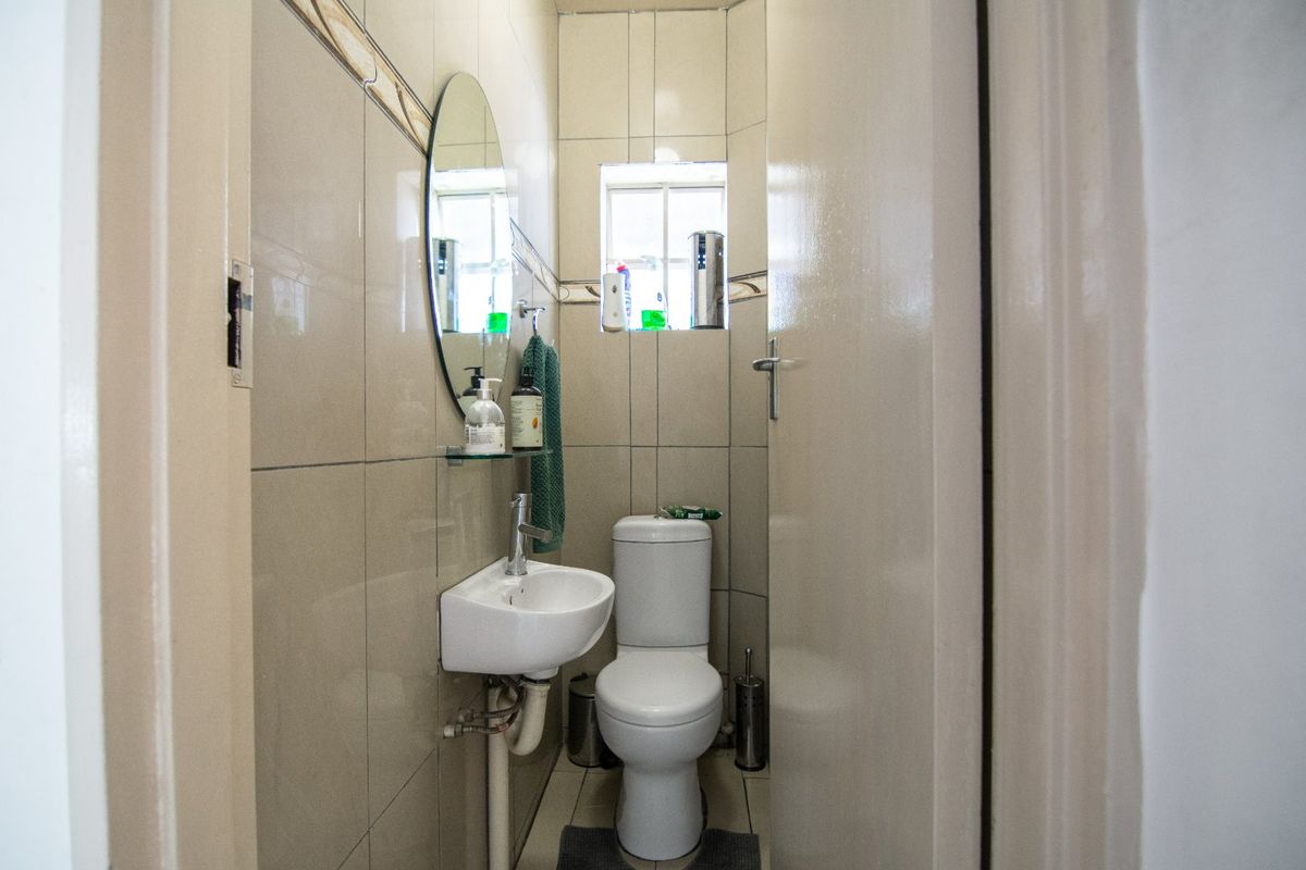 A compact guest bathroom featuring tiled walls, a wall-mounted basin, and a standard toilet.