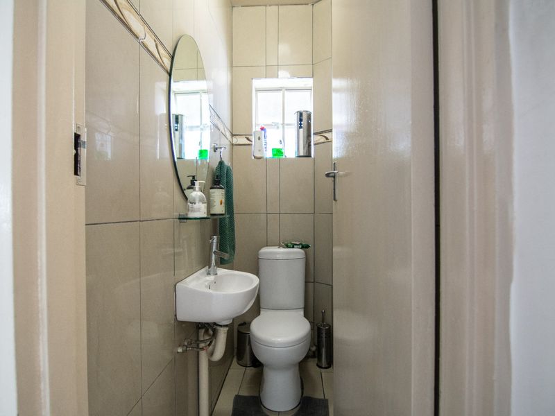 A compact guest bathroom featuring tiled walls, a wall-mounted basin, and a standard toilet.