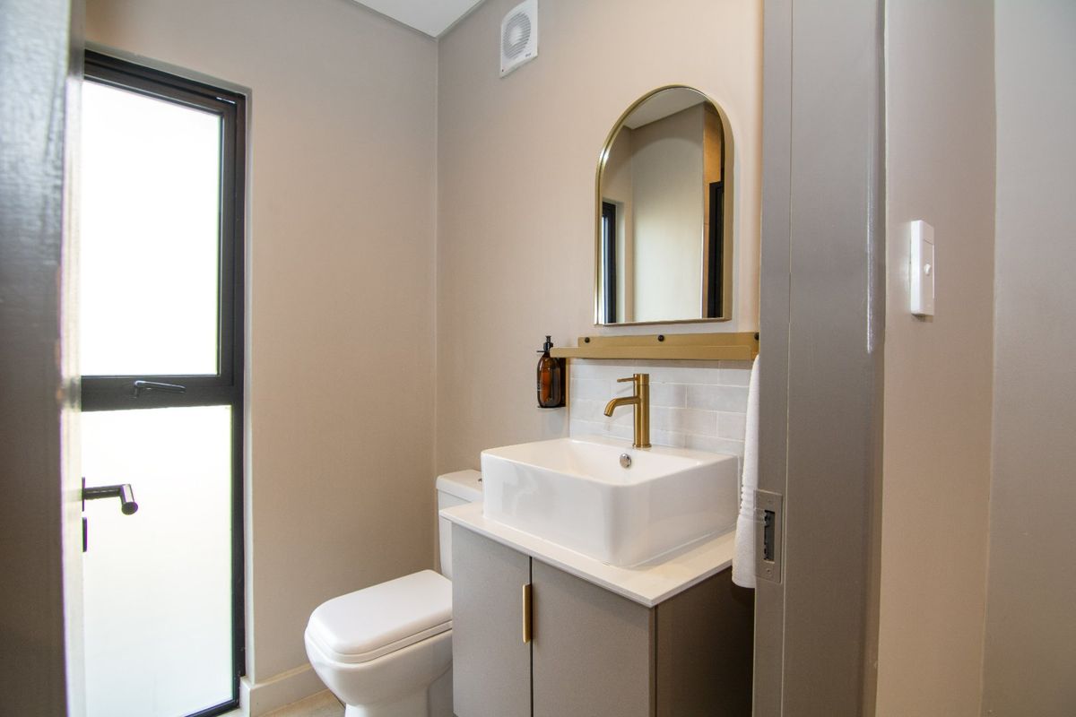 Modern bathroom featuring a sleek vanity with vessel sink, brass fixtures, and a neutral color palette.
