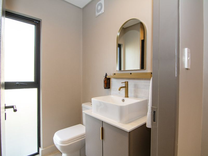 Modern bathroom featuring a sleek vanity with vessel sink, brass fixtures, and a neutral color palette.