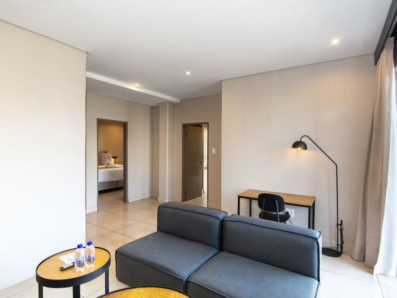 A modern, well-maintained living area featuring neutral walls, tiled flooring, recessed lighting, and direct access to an outdoor space via a sliding glass door.