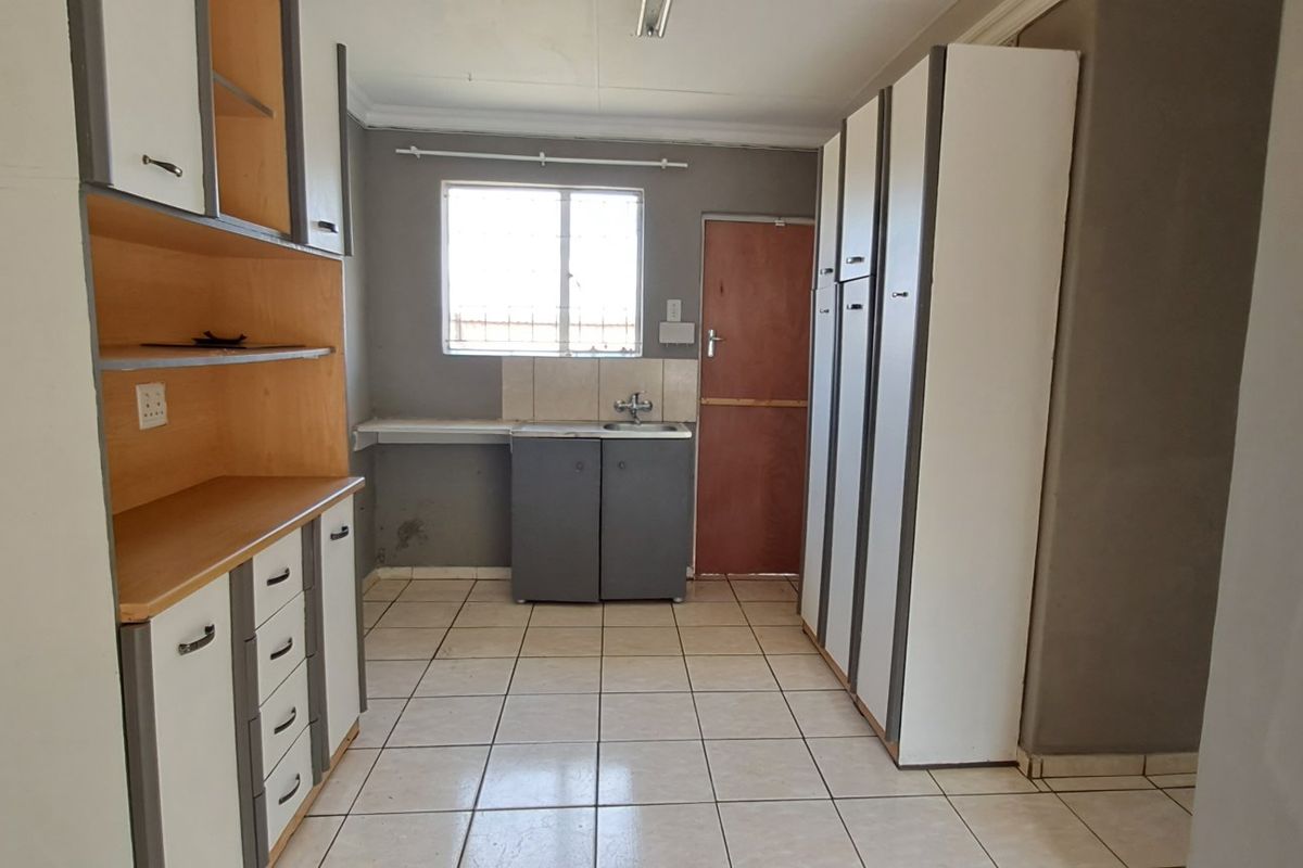A functional kitchen space featuring built-in cabinetry, tiled flooring, and a sink, offering a blank canvas for potential renovation and modernization.