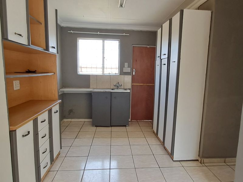 A functional kitchen space featuring built-in cabinetry, tiled flooring, and a sink, offering a blank canvas for potential renovation and modernization.