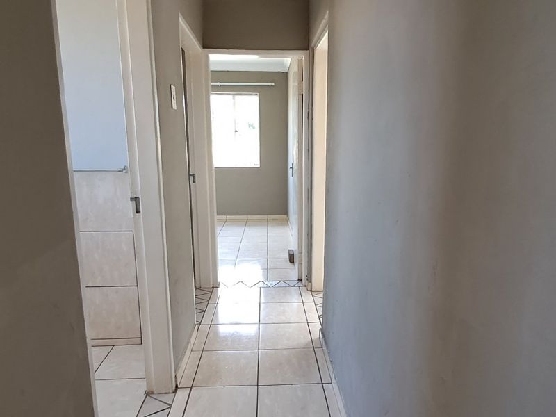 A vacant hallway featuring tiled flooring and access to multiple rooms, currently showing unfinished wall surfaces.