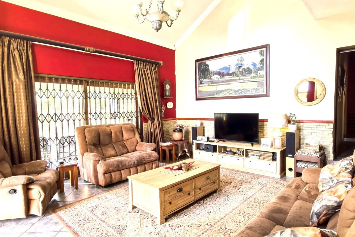 Spacious living room featuring a vaulted ceiling, tiled flooring, and a large sliding glass door with security gate leading to the exterior.