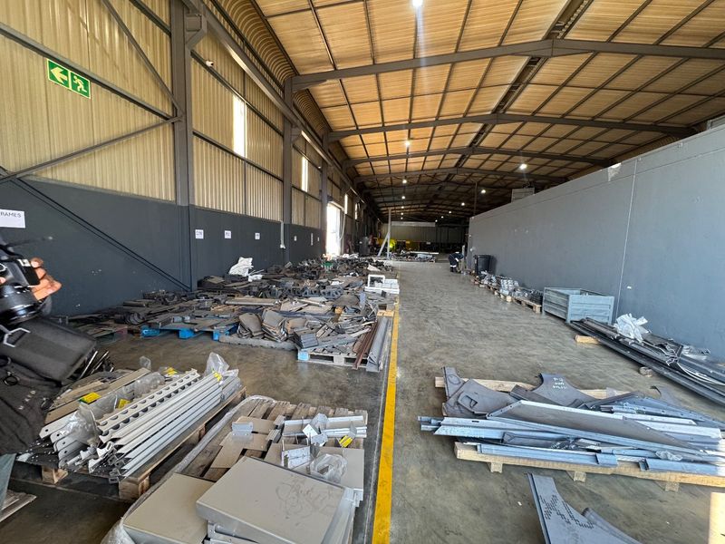 Spacious industrial warehouse facility featuring high-clearance steel portal frame construction, concrete flooring, and functional overhead lighting, suitable for manufacturing or storage operations.
