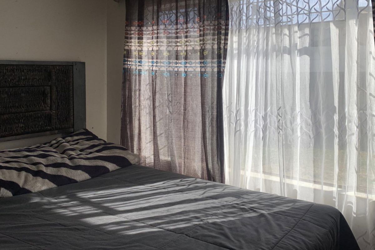 A bedroom featuring natural light filtering through layered curtains, creating a soft atmosphere.