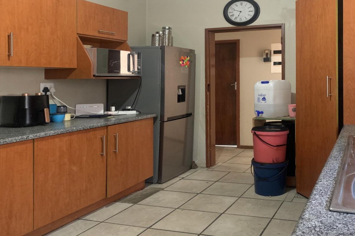 A functional kitchen featuring laminate cabinetry, granite-look countertops, and a double bowl stainless steel sink with tiled flooring.