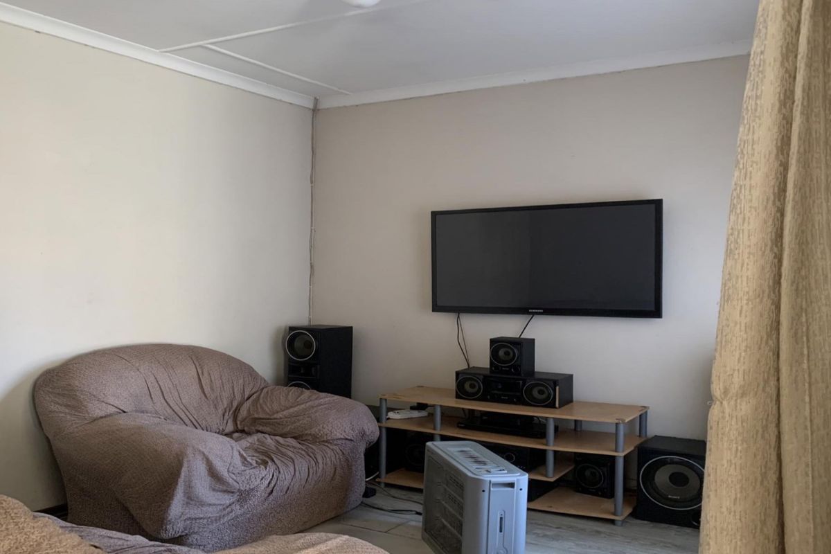 A living room area featuring neutral wall finishes and a wall-mounted television setup.