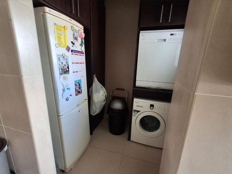 A functional laundry area featuring built-in cabinetry and tiled finishes, providing dedicated space for laundry appliances.